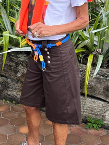 Person standing outdoors with greenery and a paved walkway